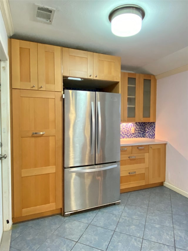 kitchen with stainless steel refrigerator, light brown cabinetry, decorative backsplash, and light tile patterned floors