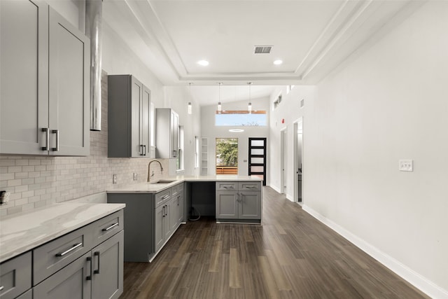 kitchen with tasteful backsplash, sink, gray cabinetry, lofted ceiling, and dark hardwood / wood-style flooring