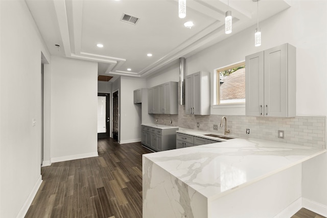 kitchen with decorative backsplash, sink, light stone counters, dark hardwood / wood-style flooring, and gray cabinets