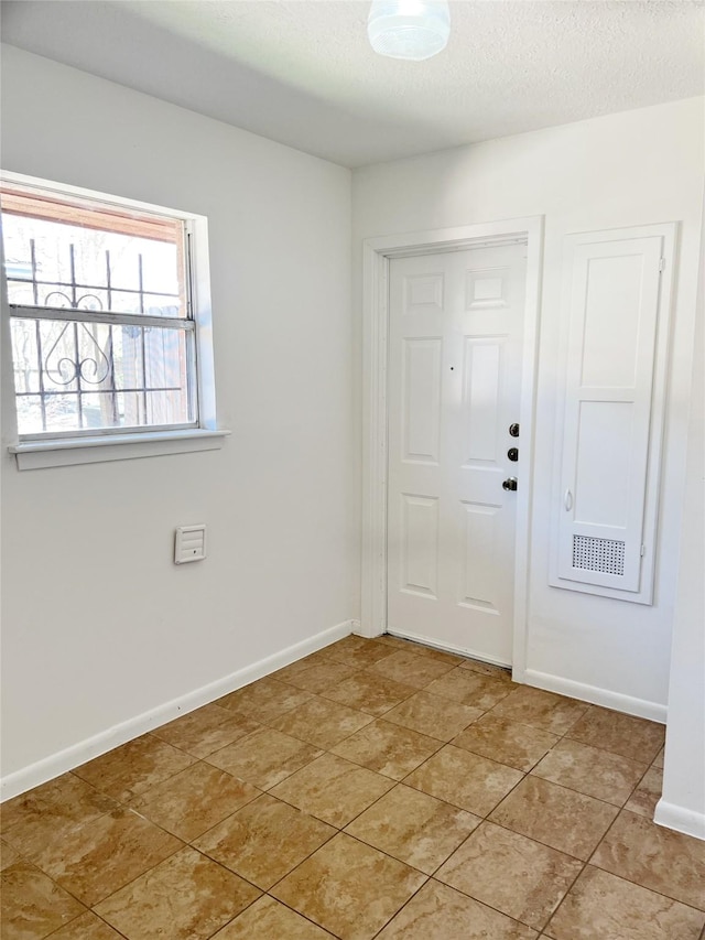 entrance foyer with a textured ceiling, light tile patterned floors, and baseboards