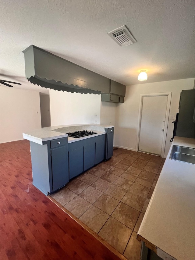 kitchen featuring gas stovetop, light countertops, visible vents, a textured ceiling, and blue cabinets