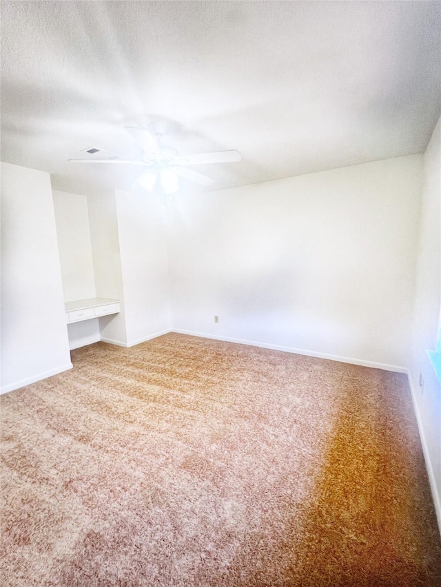 carpeted spare room featuring baseboards, a ceiling fan, and a textured ceiling