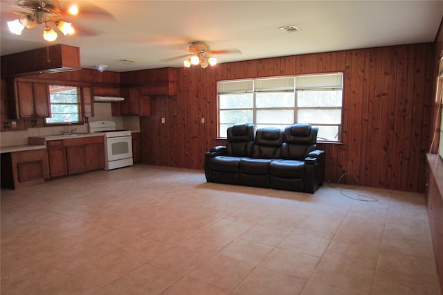 living room featuring wooden walls, sink, and ceiling fan