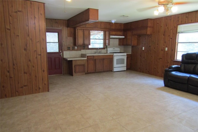 kitchen featuring ceiling fan, wood walls, sink, and white gas range oven