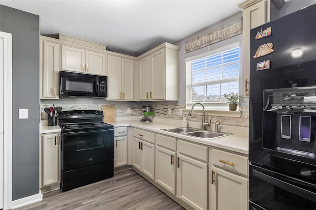 kitchen featuring sink, black appliances, and cream cabinets