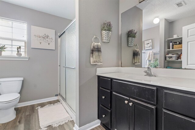 bathroom with wood-type flooring, an enclosed shower, a textured ceiling, vanity, and toilet