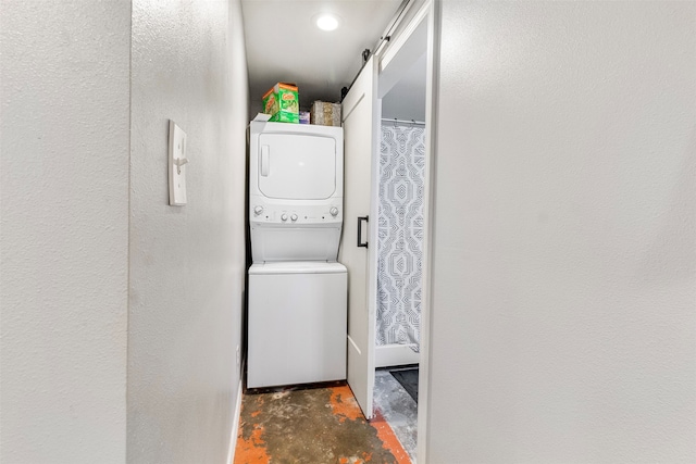 laundry area featuring a barn door and stacked washer and dryer