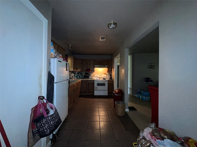 kitchen with range, white fridge, and dark tile patterned floors