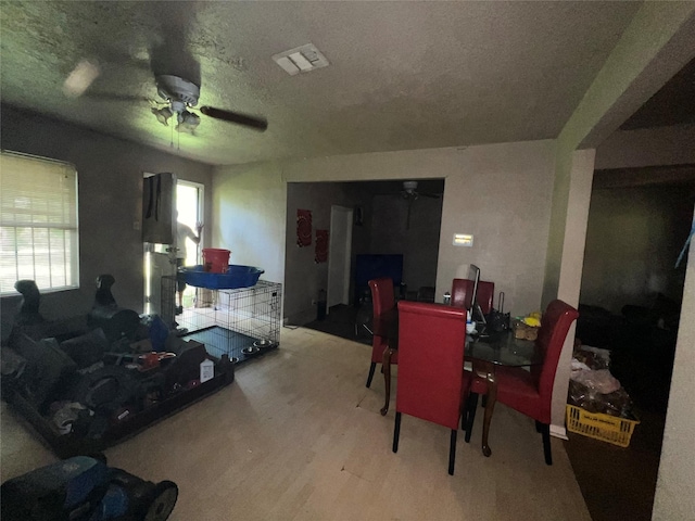 dining space with ceiling fan, a textured ceiling, wood finished floors, and visible vents