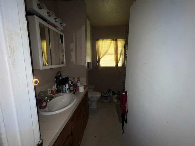 bathroom with toilet, vanity, and tile patterned floors