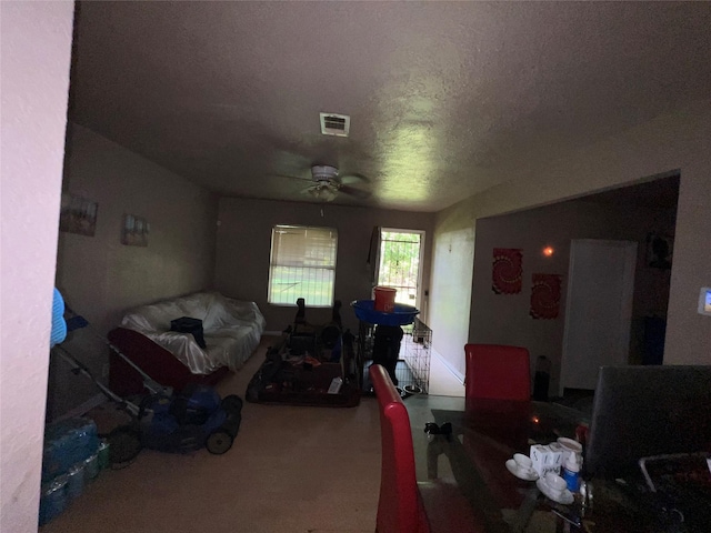 living room featuring carpet floors, a textured ceiling, visible vents, and a ceiling fan