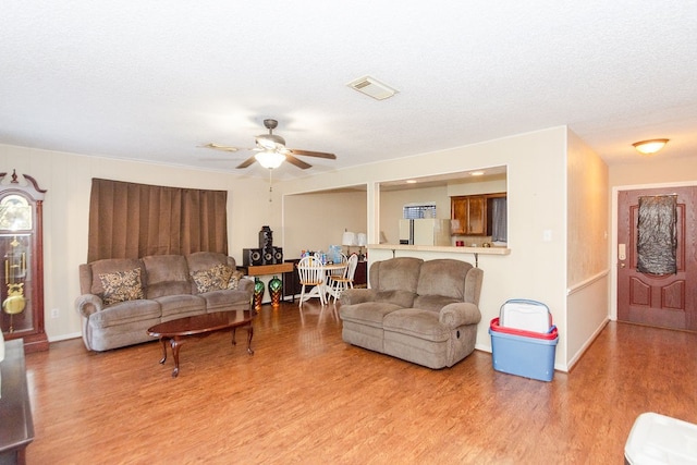 living room with a textured ceiling, ceiling fan, and hardwood / wood-style floors