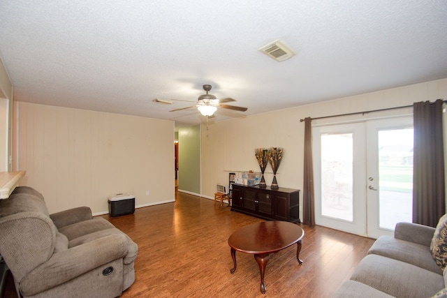 living room with ceiling fan, hardwood / wood-style flooring, french doors, and a textured ceiling