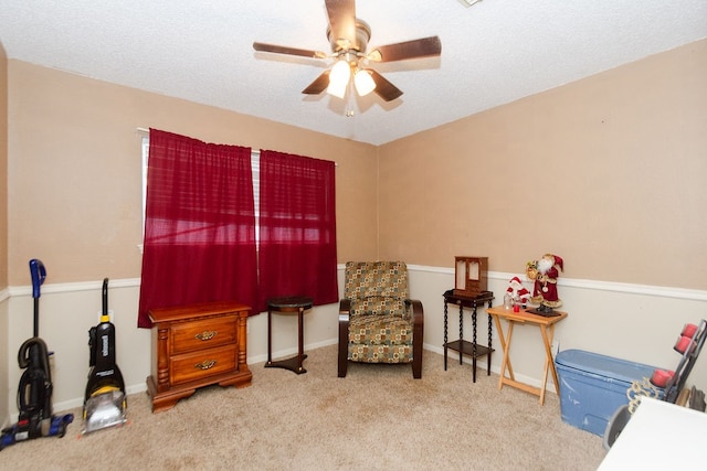 sitting room with ceiling fan, carpet, and a textured ceiling