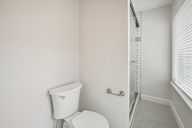 bathroom featuring toilet, tile patterned flooring, and a shower with door