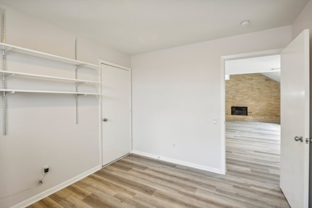 washroom featuring brick wall, light wood-type flooring, and a fireplace