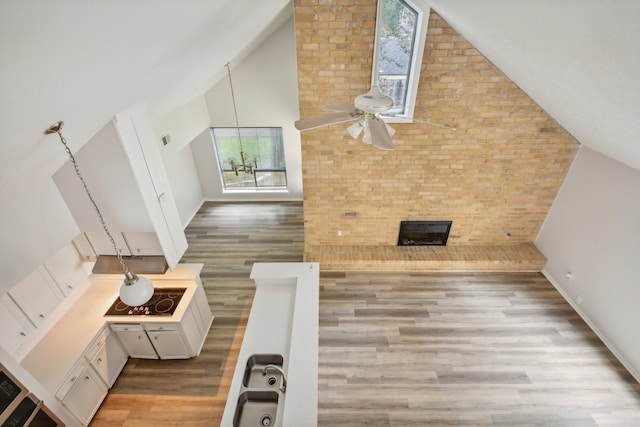 interior space with a wealth of natural light, a large fireplace, light hardwood / wood-style flooring, and high vaulted ceiling