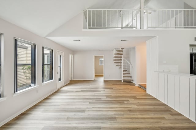 unfurnished living room featuring light wood-type flooring and high vaulted ceiling