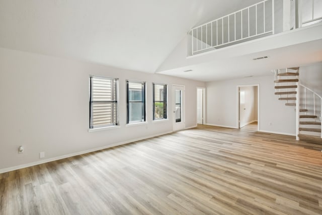 unfurnished living room featuring high vaulted ceiling and light hardwood / wood-style floors