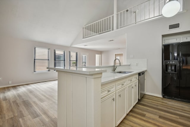 kitchen with dishwasher, kitchen peninsula, sink, black refrigerator with ice dispenser, and light hardwood / wood-style floors