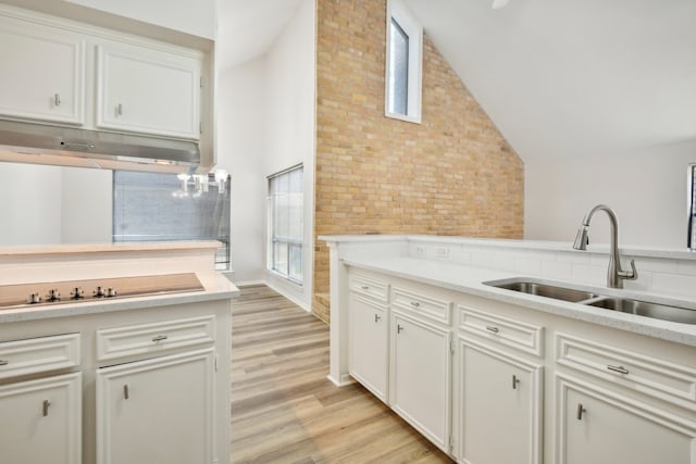 kitchen with white cabinetry, light hardwood / wood-style flooring, brick wall, and sink