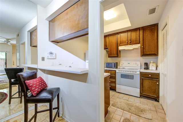 kitchen with a breakfast bar area, ceiling fan, and electric stove