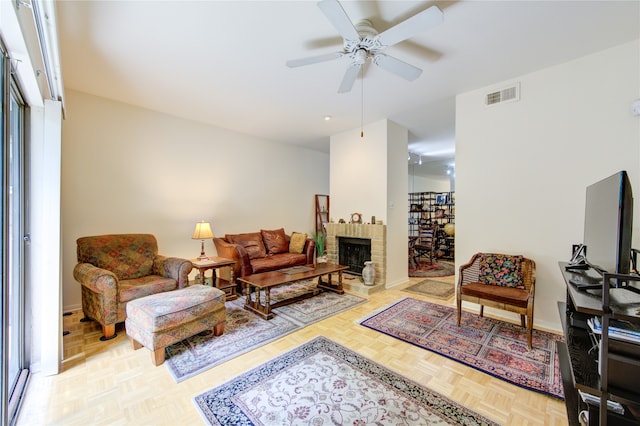 living room featuring ceiling fan, light parquet floors, and a brick fireplace