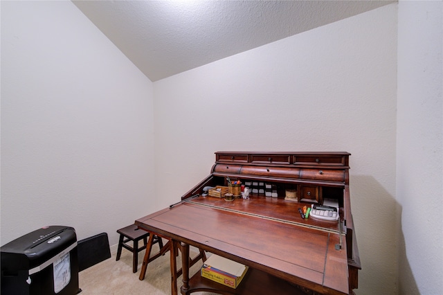 home office featuring lofted ceiling, light carpet, and a textured ceiling