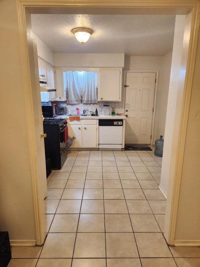 kitchen featuring black gas range oven, white cabinets, white dishwasher, and light tile patterned floors