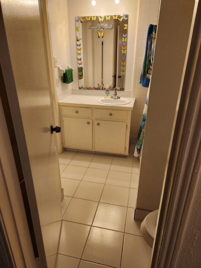 bathroom with tile walls, tile patterned flooring, vanity, and toilet