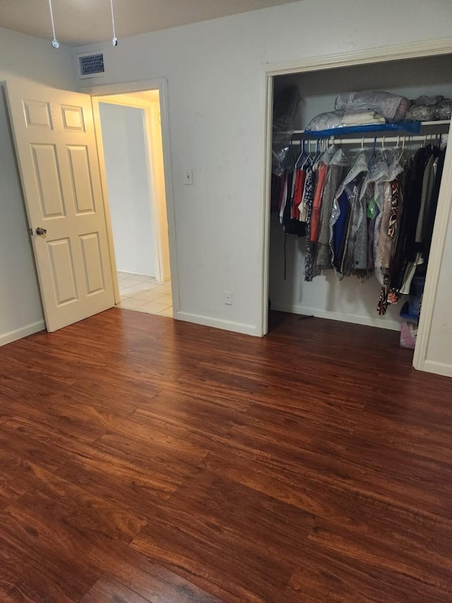 unfurnished bedroom featuring a closet and dark wood-type flooring