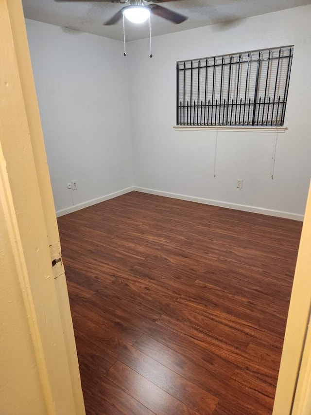 empty room with ceiling fan and dark hardwood / wood-style flooring