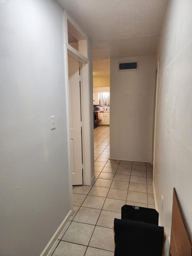 corridor with light tile patterned floors and a textured ceiling