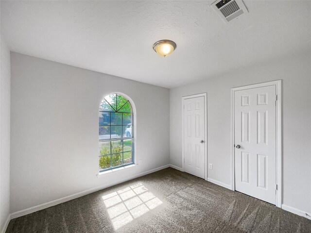 unfurnished bedroom featuring multiple closets and carpet flooring