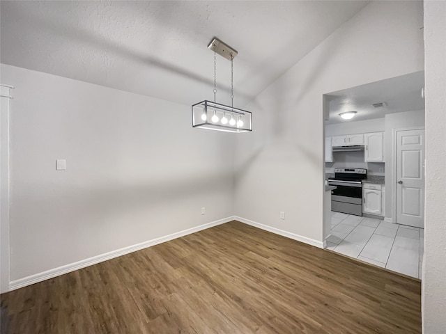 unfurnished dining area featuring light hardwood / wood-style floors and lofted ceiling