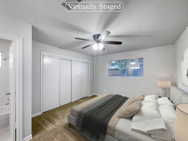 carpeted bedroom with a textured ceiling, a closet, ceiling fan, and ensuite bathroom