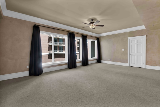 empty room featuring ceiling fan, ornamental molding, light carpet, and a tray ceiling