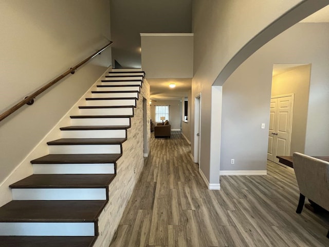 stairs with hardwood / wood-style flooring and a towering ceiling