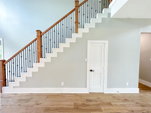 staircase with hardwood / wood-style floors and a high ceiling