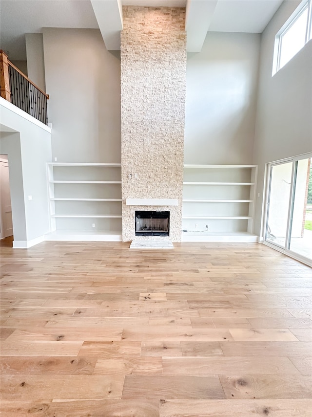 unfurnished living room with plenty of natural light, light hardwood / wood-style flooring, and a large fireplace