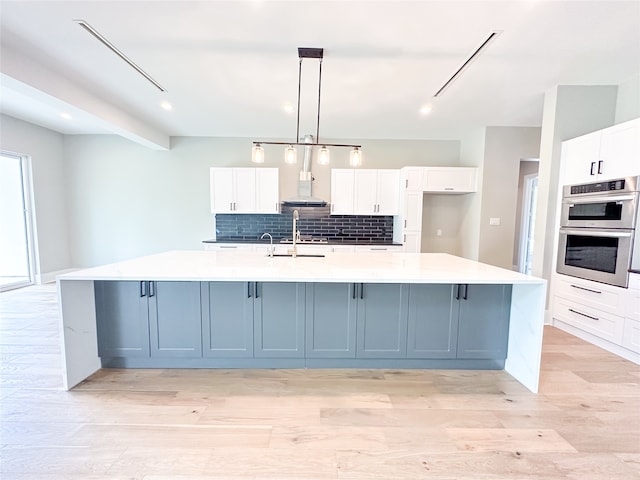 kitchen with double oven, a large island, and white cabinets