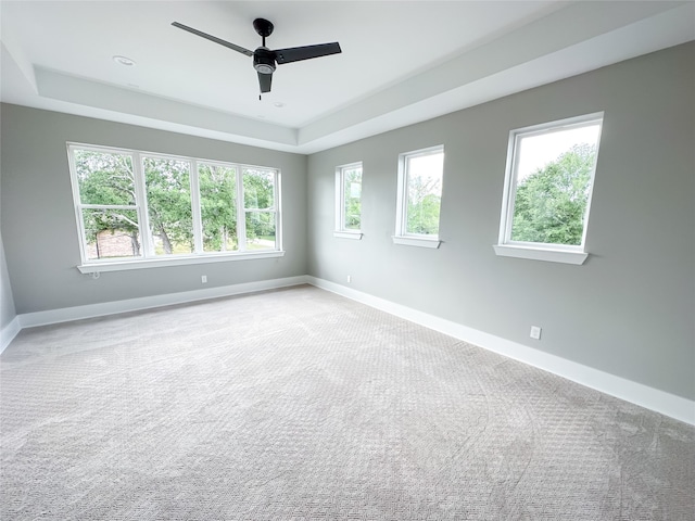 carpeted spare room featuring ceiling fan and a tray ceiling