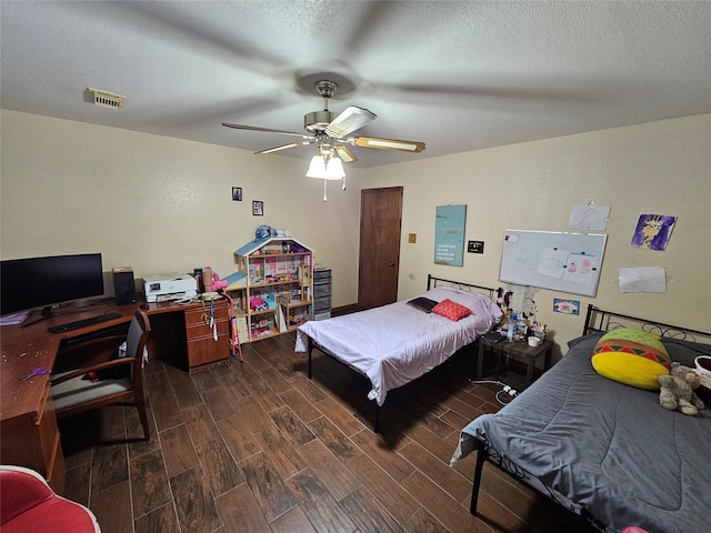 bedroom with a textured ceiling, ceiling fan, and dark hardwood / wood-style floors