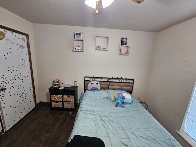 bedroom with ceiling fan, a textured ceiling, and dark hardwood / wood-style floors