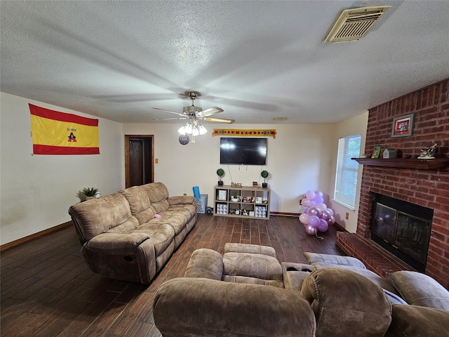 living room with a brick fireplace, dark hardwood / wood-style flooring, a textured ceiling, ceiling fan, and brick wall