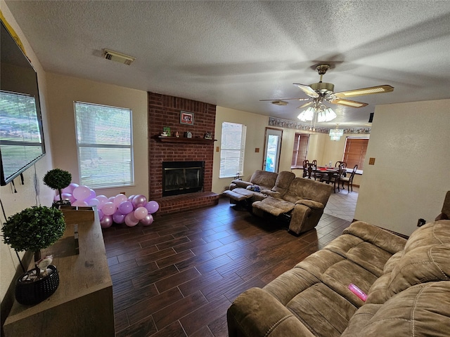 living room featuring hardwood / wood-style floors, brick wall, a fireplace, a textured ceiling, and ceiling fan