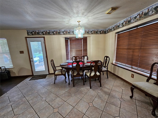 tiled dining room with a textured ceiling and an inviting chandelier