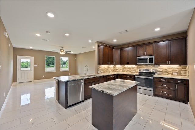 kitchen featuring appliances with stainless steel finishes, backsplash, sink, light tile patterned floors, and kitchen peninsula