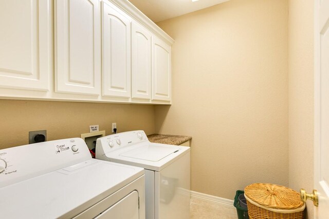 laundry area with light tile patterned flooring, washing machine and clothes dryer, and cabinets