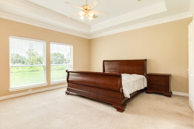 bedroom featuring ceiling fan, a raised ceiling, crown molding, and light carpet